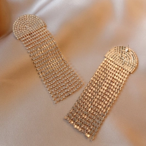 Close-up of golden jellyfish tassel earrings with sparkling rhinestones on satin fabric