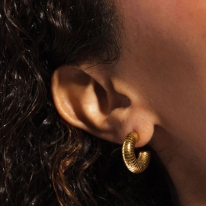 Vue détaillée de créoles en acier titane plaqué or 14 carats avec texture spirale sur modèle