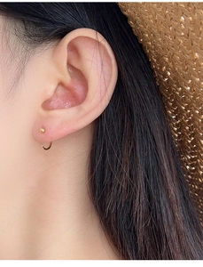 Macro detail of minimalist S925 silver C-shape stud earring with gold finish on ear