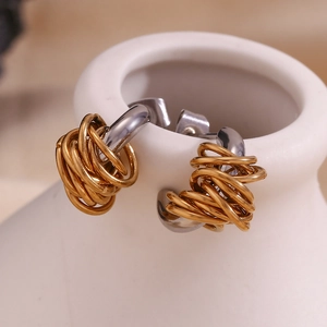 Detail of creative mixed-metal bird nest earrings with gold and silver coiled wire
