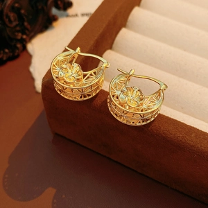 Close-up of golden hollow mesh earrings with flower design on dark velvet stand