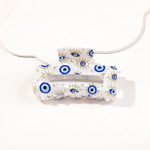 Detail shot of Evil Eye print hair claw clip with gold star and moon patterns on white marble