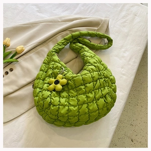 Macro detail of grass green quilted cloud bag featuring soft texture and flower charm