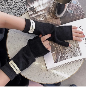 Detail of black knitted fingerless gloves with a nice moment label on a cozy table