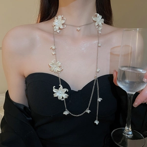 Detail view of a luxury pearl and acrylic flower waist chain worn by a model