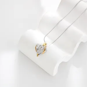 Macro detail of a heart pendant featuring textured gold and silver two-tone metal finish