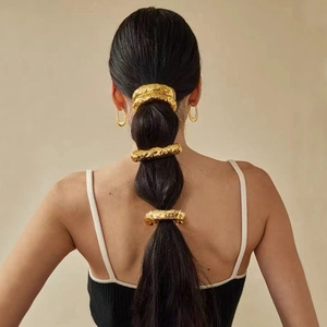 Detailed view of irregular textured gold hair clips layered on a bubble ponytail hairstyle