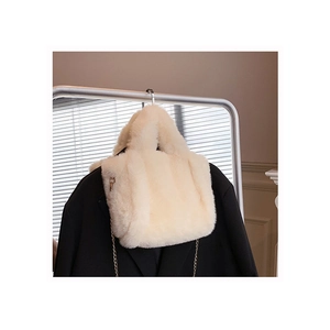 Sac fourre-tout chic en peluche beige avec bandoulière chaîne en métal dans un salon