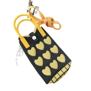 Detailed view of knitted cat heart mini bag with yellow strap and white button closure