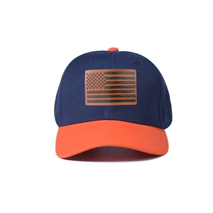Detail of USA flag patch on navy and orange contrast baseball cap with stitched brim