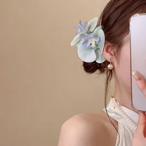Elegant light blue fabric flower hair clip with pearls shown on a woman hairstyle
