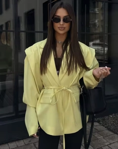 Detail of waist tie and shoulder pads on a bright yellow women blazer jacket