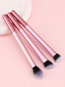 Gros plan de trois pinceaux de maquillage professionnels or rose avec poils bicolores noir et blanc