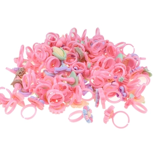 Close-up of assorted pink plastic girl's toy rings featuring flower and ice cream shapes