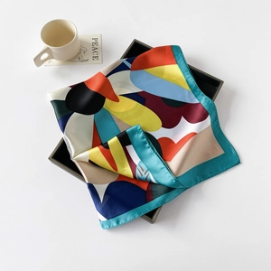Detailed view of 70x70cm colorful geometric floral silk scarf folded in a tray