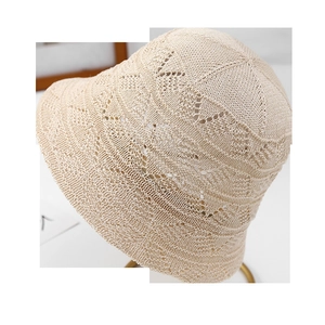 Detail of cream white crochet bucket hat with hollow-out diamond pattern on metal stand