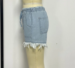 Détail d'un short en jean bleu clair avec taille élastique à cordon et ourlet à franges