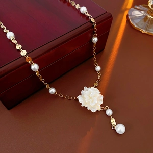Detailed close-up of a French style pearl necklace with flower pendant on a dark desk