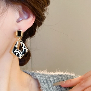 Détail de boucles d'oreilles géométriques en acétate léopard avec cadre doré