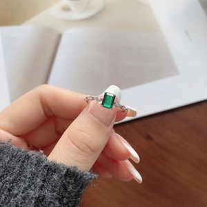 Macro shot of an emerald-cut green gemstone ring with side marquise accents