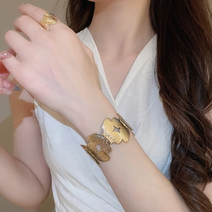 Close-up detail of golden butterfly bracelet and ring set with textured metal finish