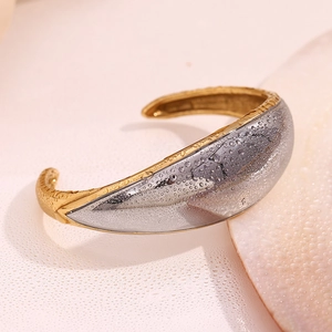 Detailed macro view of dual-tone open bangle featuring smooth silver and gold textured edges