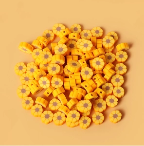 Vue détaillée de perles tournesol en pâte polymère jaune avec trous pour bijoux DIY