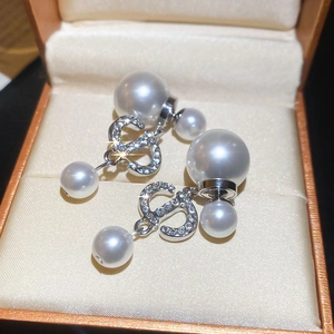 Macro shot of silver CD logo earrings with pavé crystals and elegant white pearls