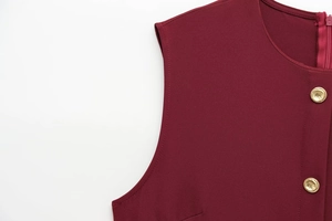 Macro view of burgundy crepe dress featuring embossed gold buttons and premium stitching