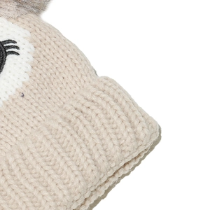 Detail of ribbed knit texture with owl embroidery and faux fur pom-pom on kids hat