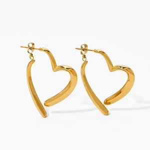 Detailed macro view of polished gold heart-shaped hoop earrings with a cross design