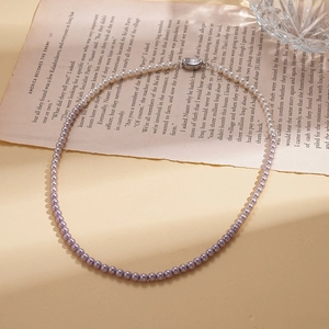Detail of purple gradient faux pearl necklace with silver clasp on vintage book page