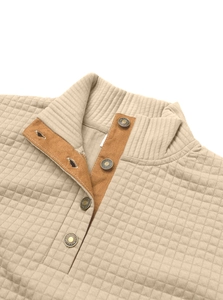 Detail of quilted texture and metal buttons on the beige pullover ribbed collar