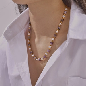 Elegant gold titanium necklace with white pearls and purple amethyst on a white shirt