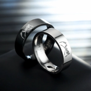 Close-up of black and silver titanium rings featuring pinky promise design and engraving