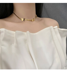 Vue détaillée d'un collier choker papillon doré sur un mannequin en haut blanc