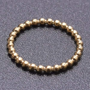 Macro shot of gold beaded stainless steel ring with 18k plating on black texture