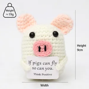 Close-up of a handmade crochet pig doll holding an inspirational card for stress relief