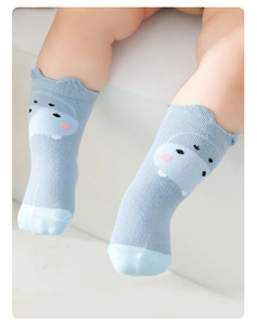 Detail of light blue baby sock featuring a knit hippo pattern and scalloped wavy edges