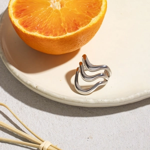 Detail of silver wavy ring on a ceramic plate with an orange for a natural aesthetic