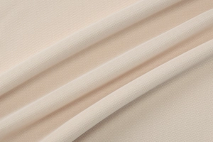 Detailed macro view of beige knitted fabric texture with soft diagonal folds and drape