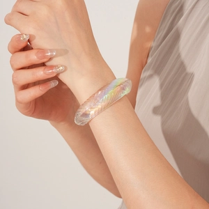 Close-up of iridescent geometric acrylic bangle with textured details on a female wrist