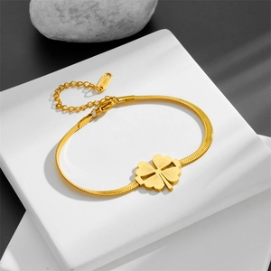 Gold stainless steel four-leaf clover bracelet with snake chain on white stone block
