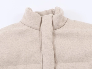 Detail shot of a stand collar oatmeal cashmere coat featuring soft wool fabric texture