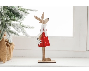 Détail d'une figurine de renne en bois avec robe à pois rouges et une écharpe blanche