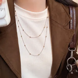 Minimalist double layer gold bead necklace styled with a brown blazer and white top