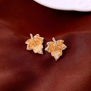Macro view of maple leaf studs with amber crystals and fine diamonds on red satin