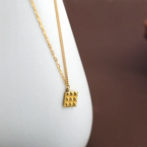 Gold chocolate square pendant necklace on asymmetric chain with grid pattern
