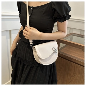 Close-up of white leather saddle bag with silver buckle worn by a model