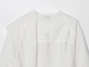 Detailed close-up of white round neck blouse featuring lightweight sheer textured fabric